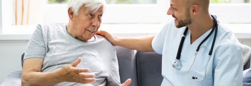 elderly senior man talking to in home care nurse